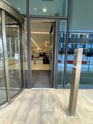 From right of revolving doors facing straight. Intercom on right. Entrance door at back.