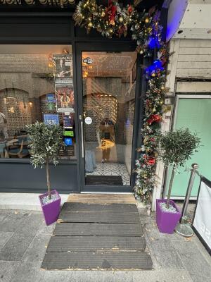 From side street facing venue. Black framed glass doors ahead. Push silver handle on left to open door inwards.