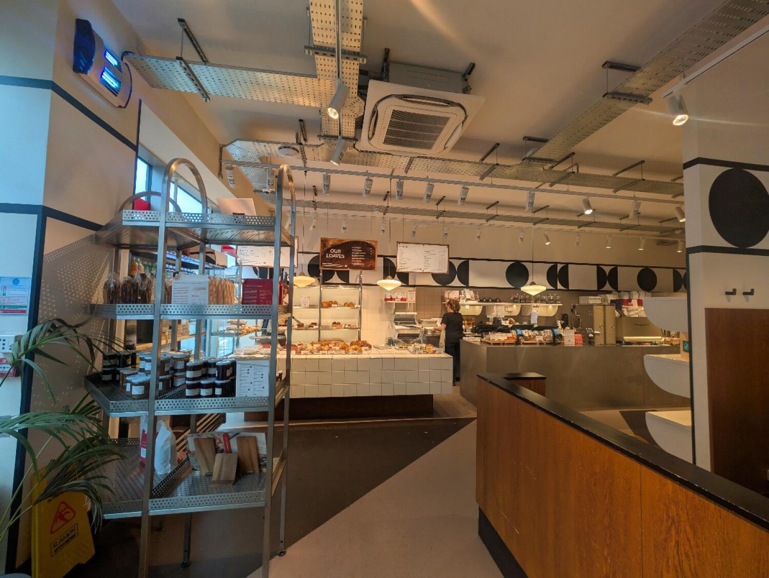 From entrance facing left. Food cart on front left. Bakery counter along back. Wooden barrier on front left.