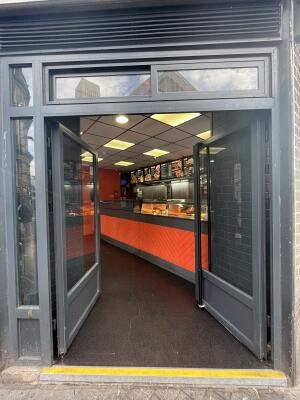 Glass double door with grey frame and handle in centre. Push to open.