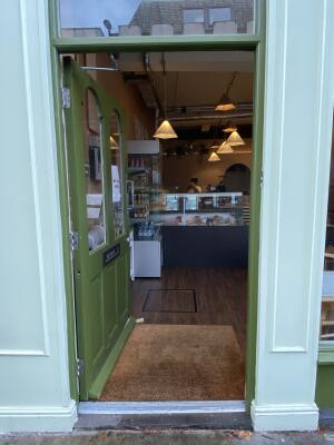 Green wooden door with glass panelling. Push silver metal handle from right to open.