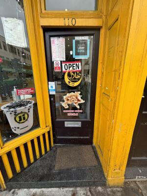 From street facing venue. Brown framed glass door ahead. Push door from left to open inwards.