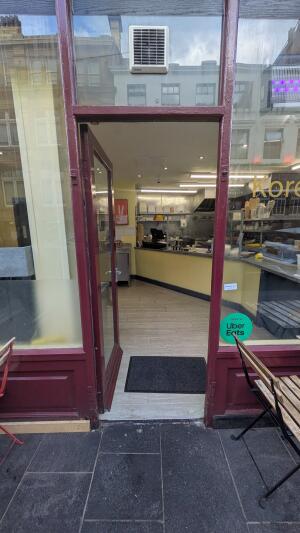 Glass door with maroon frame. Push handle on right to open