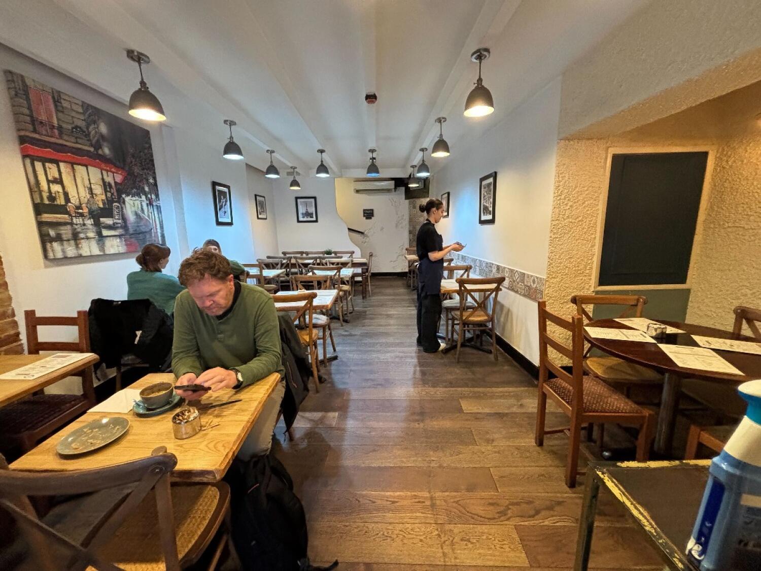From end of counter facing straight. Tables and chairs along both sides. Path in center to bathroom.