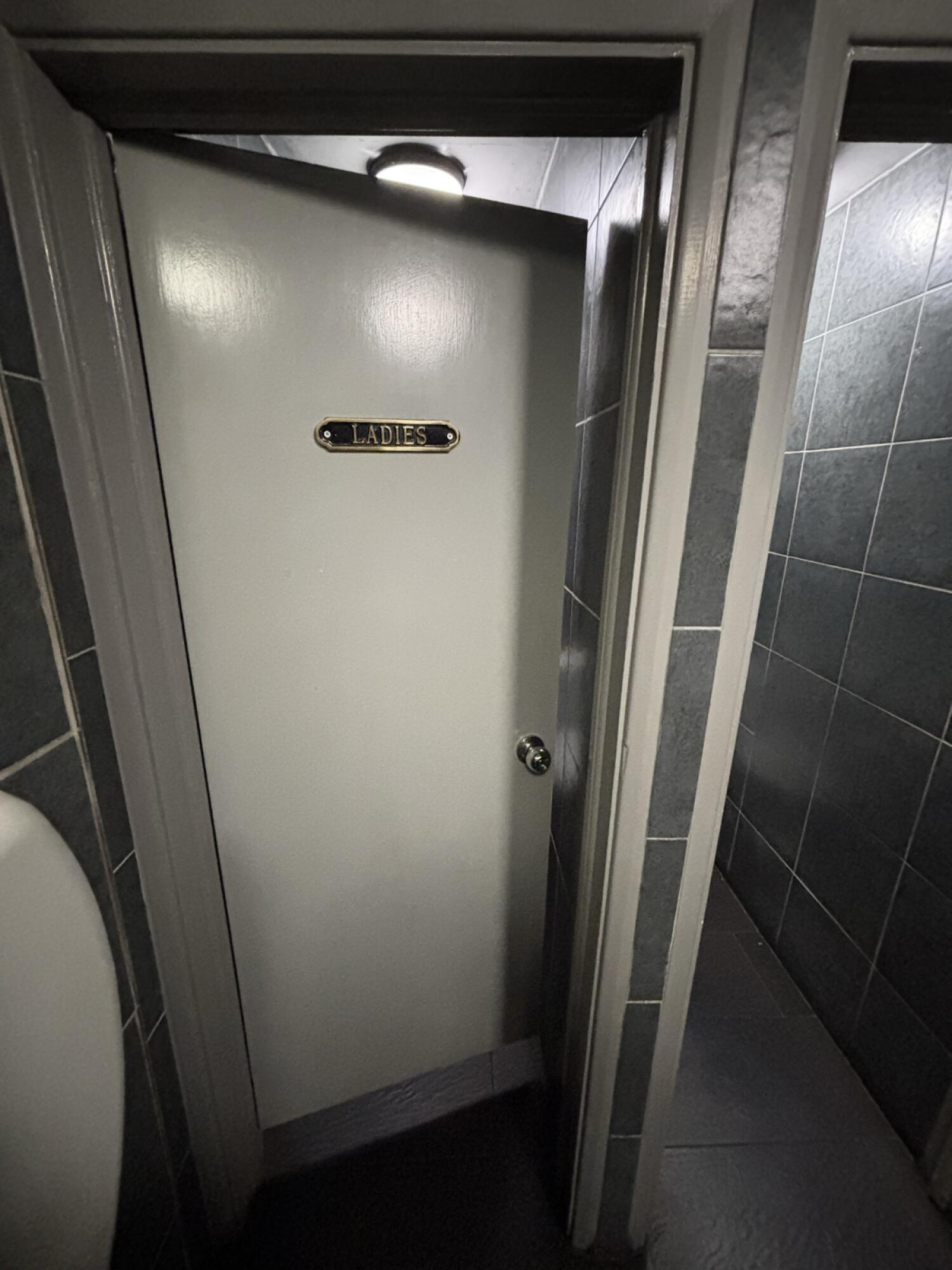 From end of baby change facing straight. Light grey door ahead. Push via handle on right to open.