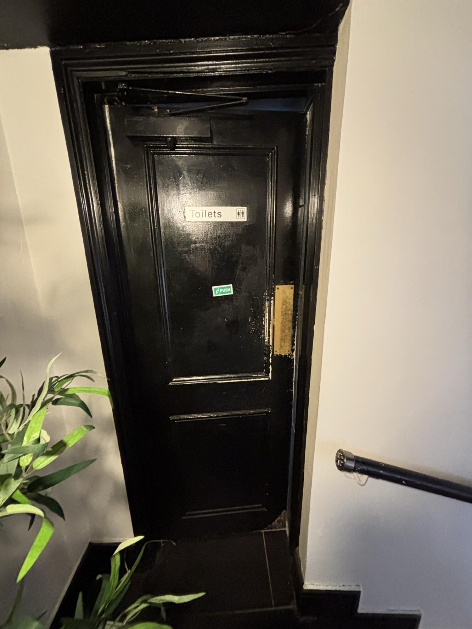 From top of steps facing right. Black door ahead. Push from right to open.