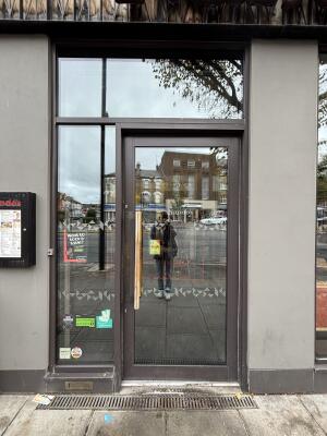 Glass door with metal frame and metal handle on left. Push to open.