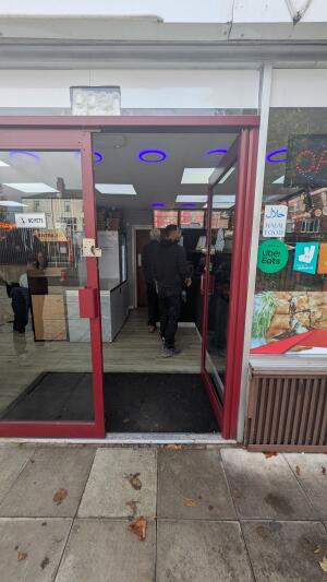 Glass door with red frame. Push handle on left to open