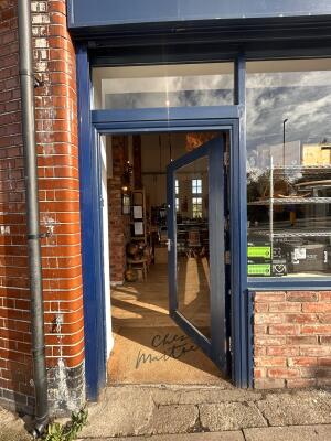 Glass door with blue metal frames ahead. Push from left to open.