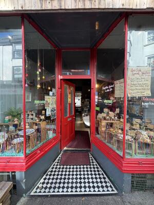 Archway ahead to red door with glass panels on back. Push from right to open.