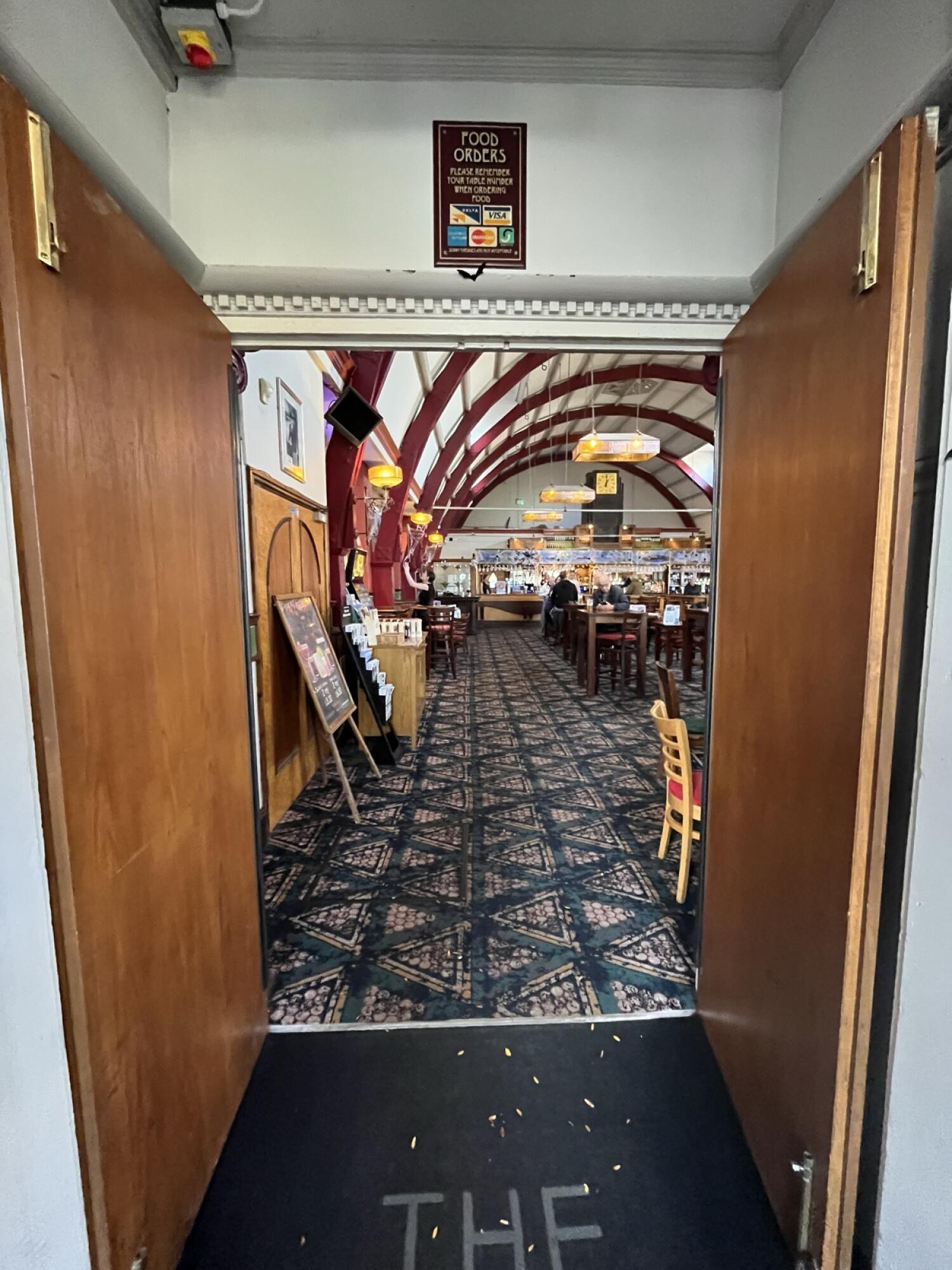 From end of path facing straight. Brown wooden double door with handles in centre. Pull to open.