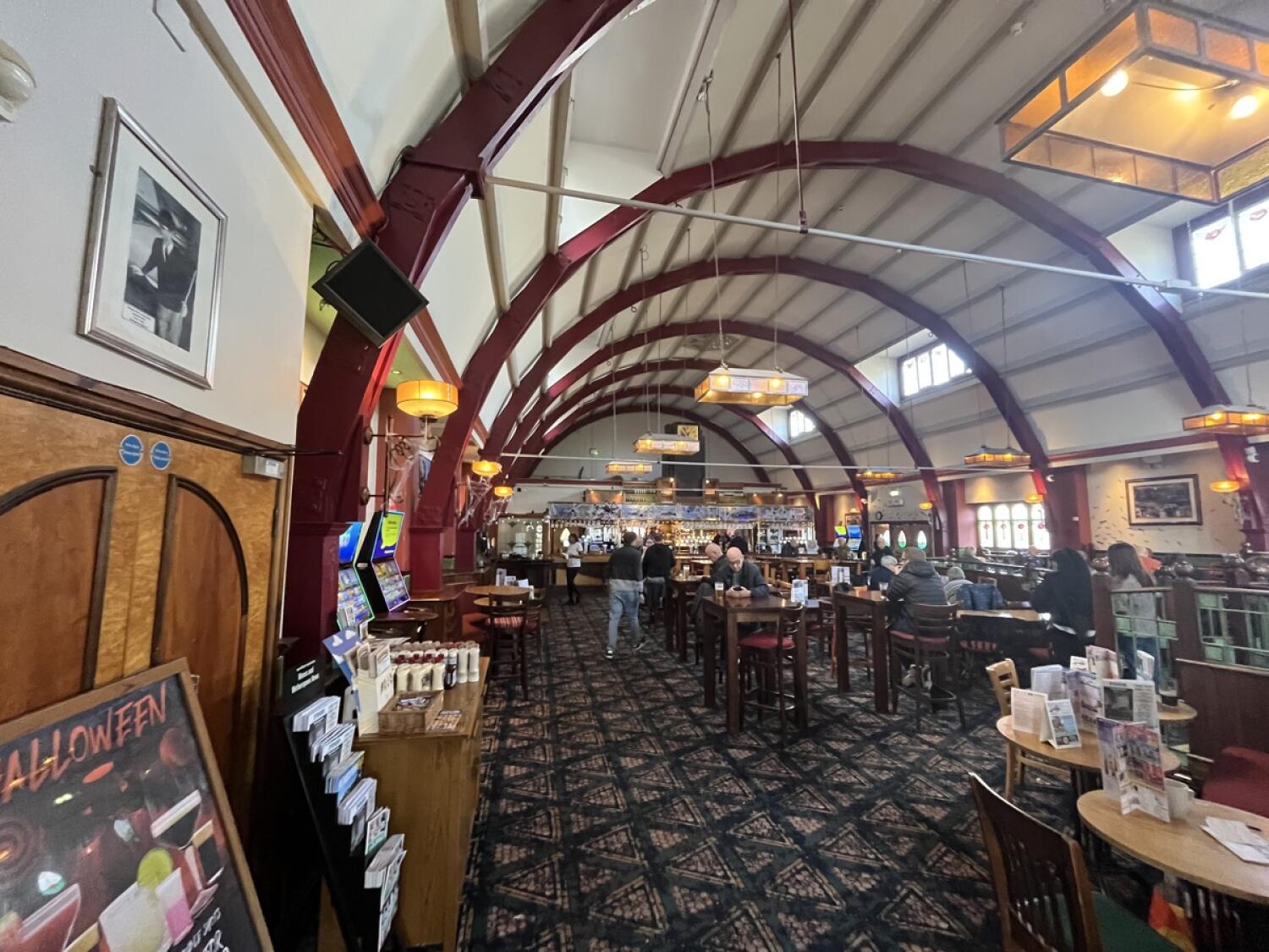 From door facing straight. Condiment table, stools and tables along left. Path in centre. Stools and tables along right.
