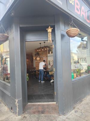 From sidewalk facing venue. Grey framed glass door ahead. Push to open.