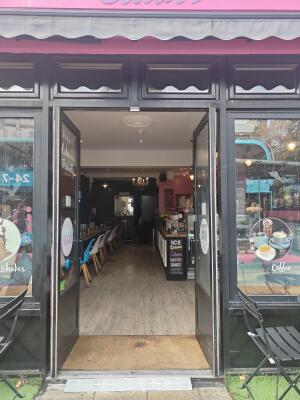 From sidewalk facing venue. Black framed glass doors ahead. Push black bar in centre to open.