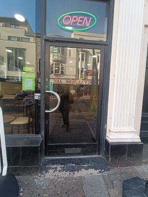 Glass door with black, metal frame. Push silver handle on left to open.