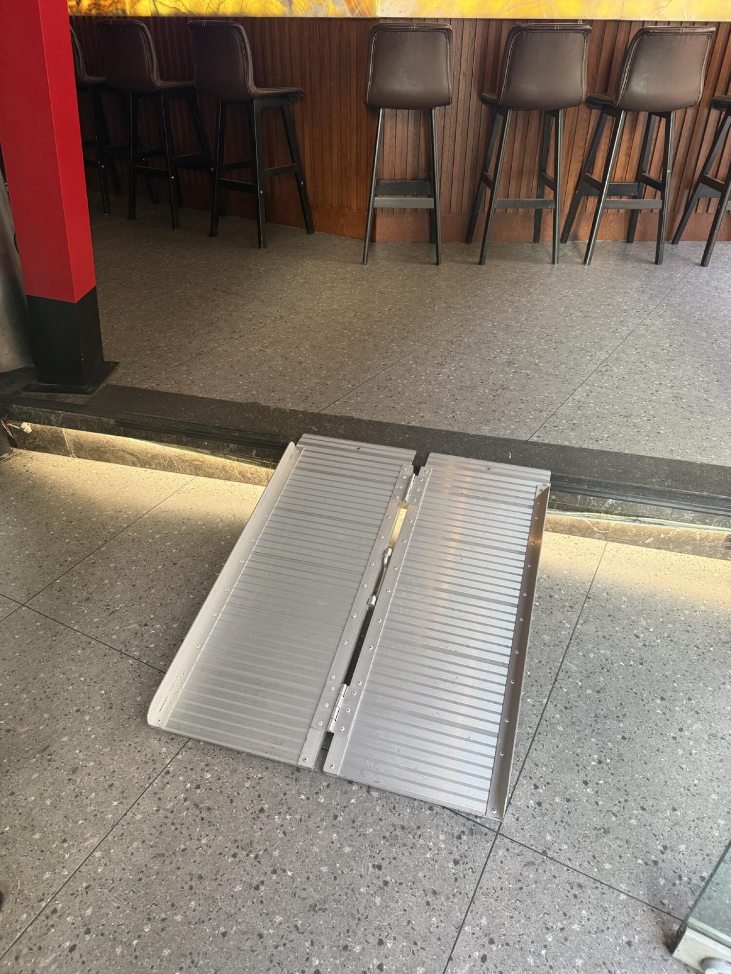 Close up of ramp sloping up to bar area with high stools along counter.