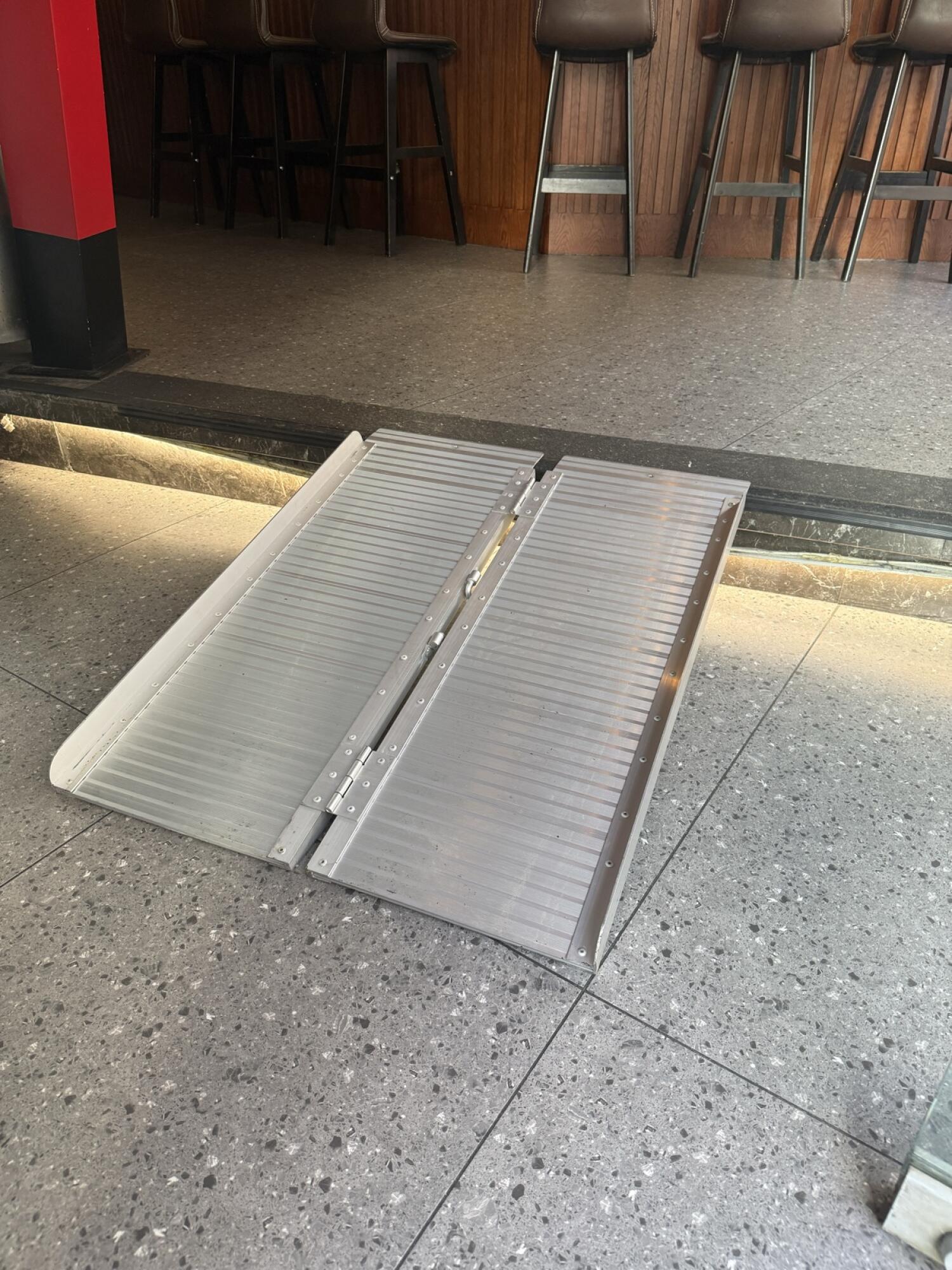 Close up of ramp sloping up to seating area with high stools.