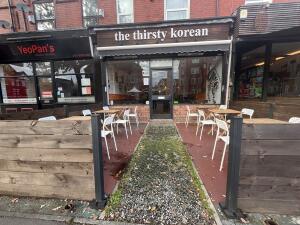 From street facing venue. Opening with wooden fence on both sides followed by a path ahead.