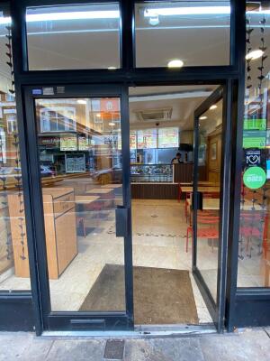 Glass doors with black metal frames ahead. Push from center to open.