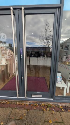 Glass door with metal frame. Push handle on left to open