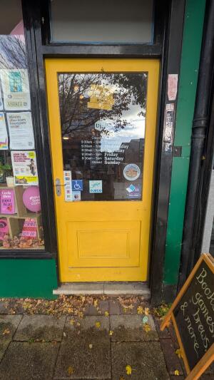 Glass door with yellow frame. Push handle on left to open