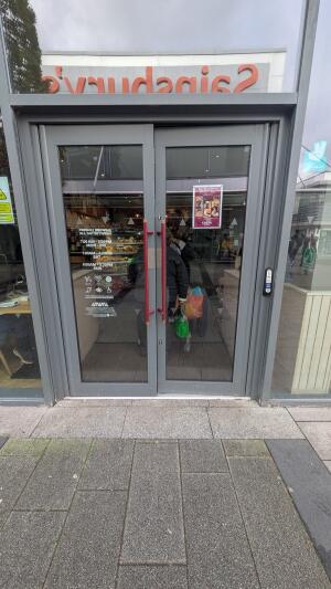 Glass doors with metal frame. Push handles in center to open. Doorbell on right.