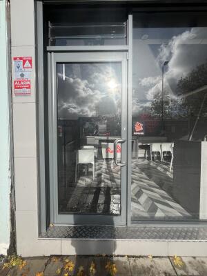 Glass door with a grey frame and handle on right. Push to open.