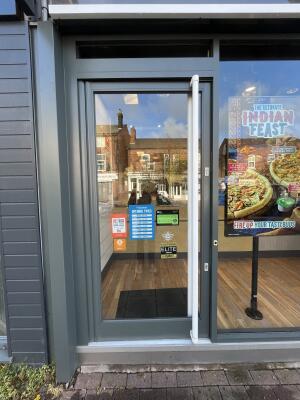 Glass door with grey frame and white handle on right. Push to open.