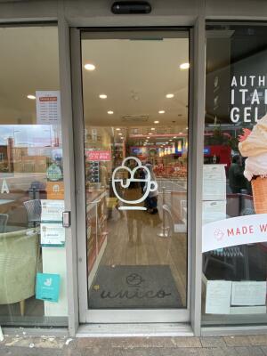 Grey framed glass sliding door. Push the silver button on left side of door to open the door. Door opens automatically from left to right.