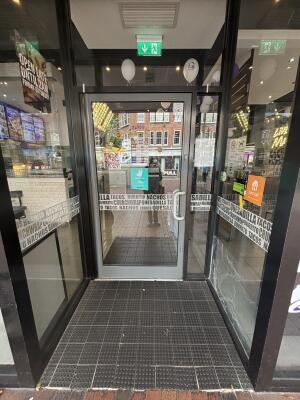 From street, facing venue. Archway ahead. Glass door with grey frame at back. Pull silver handle on right to open.