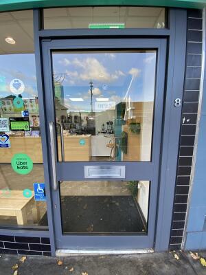 Grey framed glass door. Push the silver metal handle from left to open.