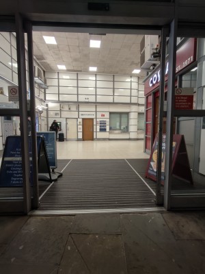 Facing grey-framed glass doors to station.