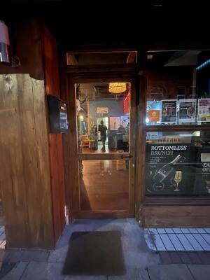 Glass door with wooden frame. Handle on right. Push to open.