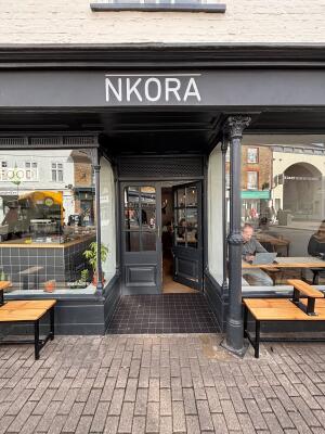 From sidewalk facing venue. Archway ahead. Door at back. Pillar on right.