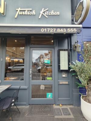 Grey framed glass panel door ahead. Push silver handle on left to open. Planter decor on right.