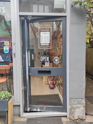 From sidewalk facing venue. Grey framed glass door ahead. Push grey handle on left to open.