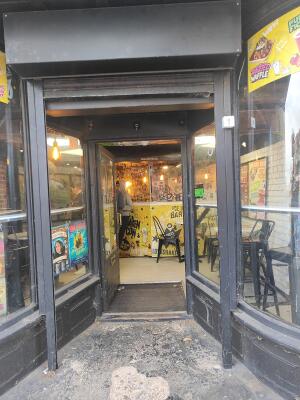 Grey framed archway to entrance. Grey framed glass door at back. Push bronze handle on right to open.