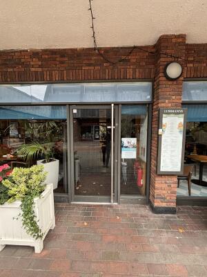 Glass door with metal frame ahead. Pull door to open via handle on right.