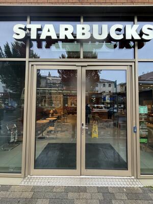 From street facing venue. Brown framed glass doors ahead. Push doors from centre to open inwards.