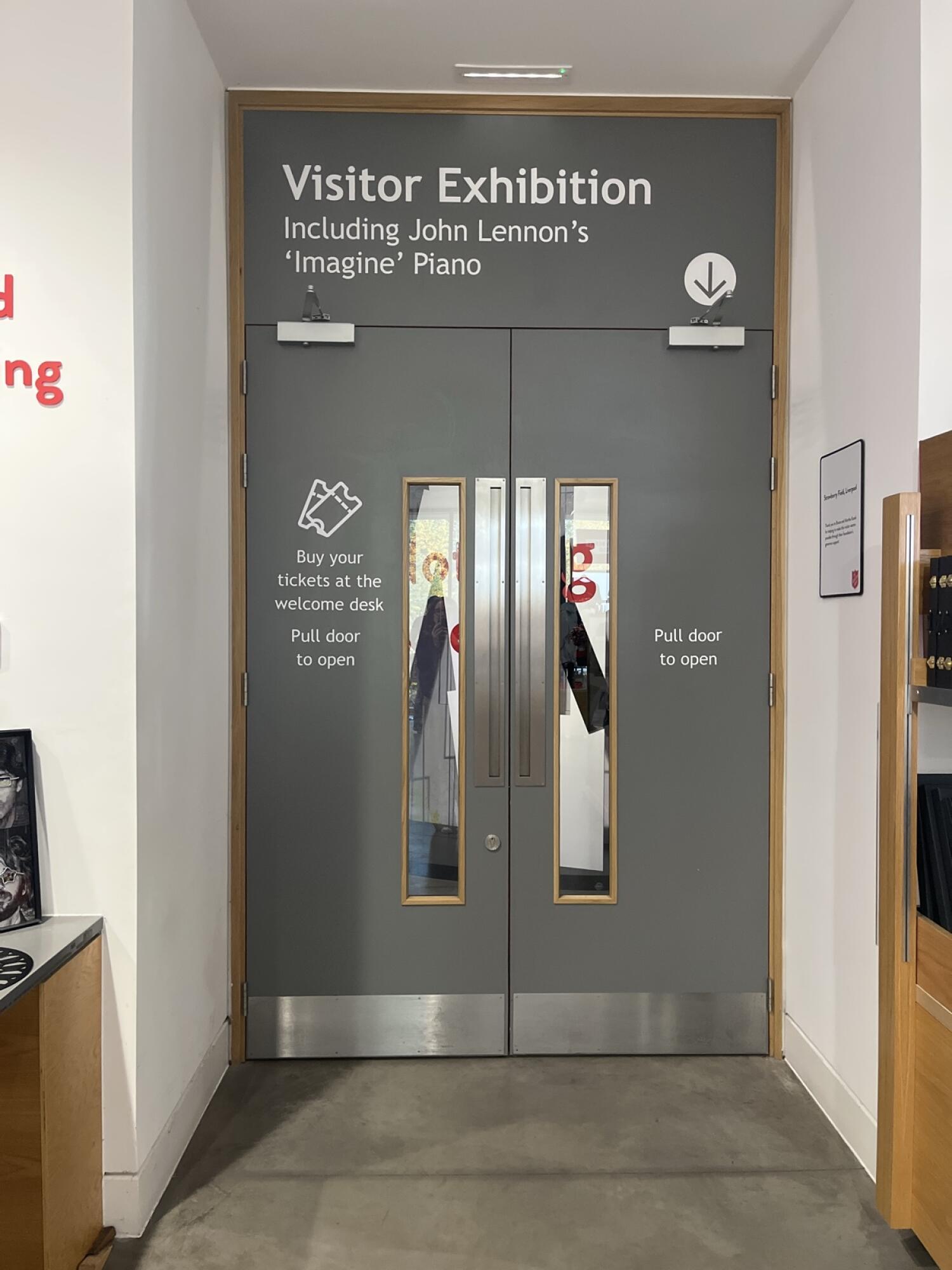 Grey wooden doors with narrow glass panels. Pull from vertical handles at centre to open.
