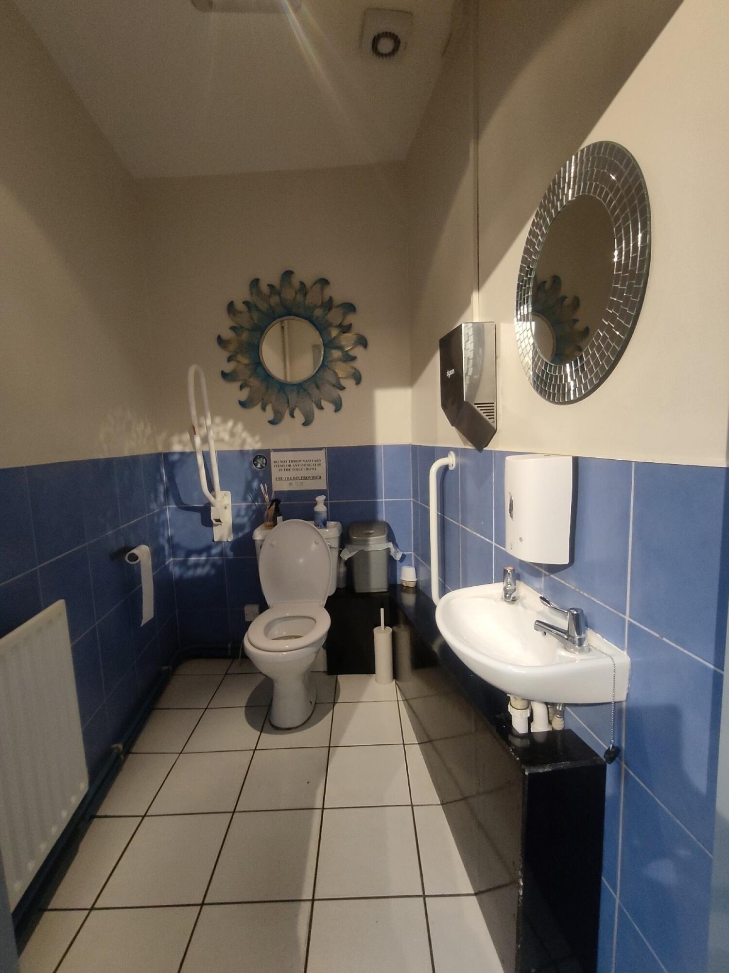 From doorway facing straight. toilet at back. Sink on right.