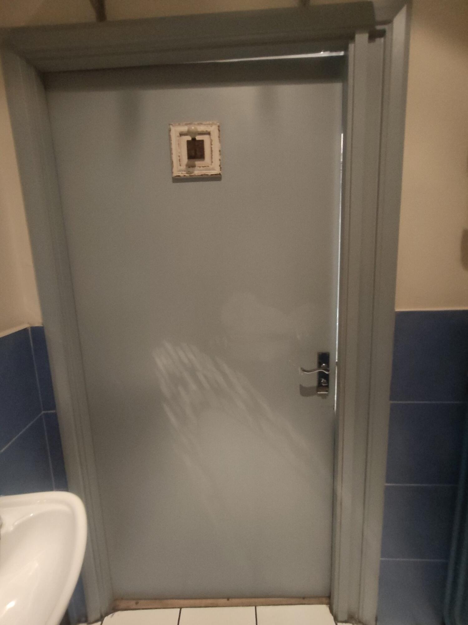 Back of door. Push silver handle on right to open.