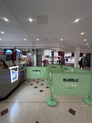 From mall corridor facing entrance. Opening on the left. Restaurant barriers on right and back.
