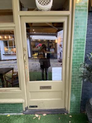 Yellow framed door with glass panelling. Push gold metal handle from left to open.