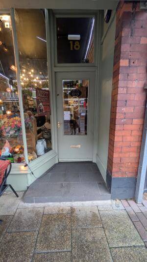 Glass door with light green frame. Push handle on left to open.
