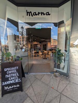Glass door with glass frames ahead. Push from right to open. Sign board on left.