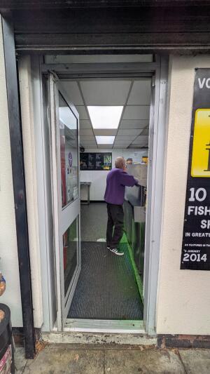 Glass door with white frame. Push handle on right to open