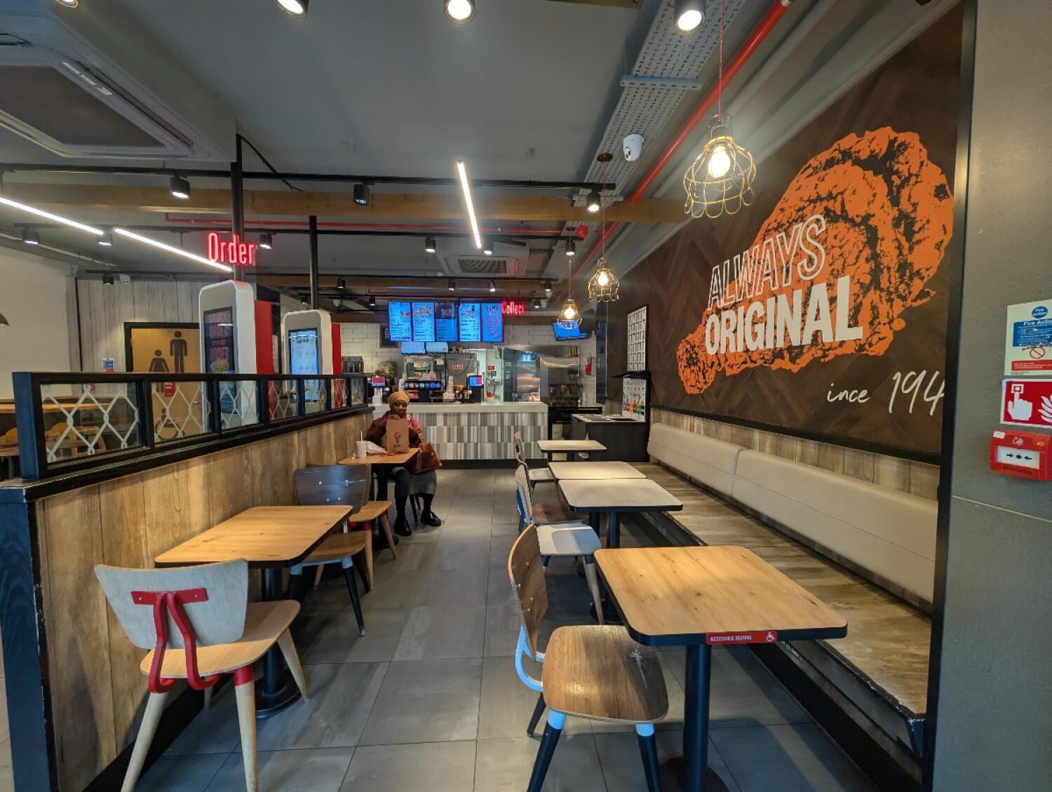 From bin facing left. Tables and chairs along left. Counter along back. Tables, chairs, and half booths along right.