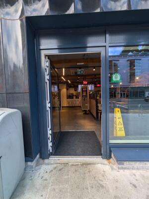 Glass door with grey metal frames ahead. Push from right to open.