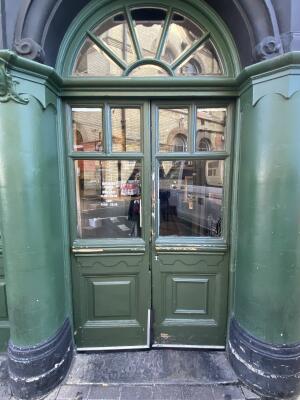 Green wooden door with glass panelling. Push from centre to open.
